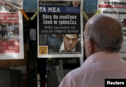 A man reads the front pages of various newspaper hanging at a kiosk in Athens, June 29, 2015.