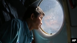Officer Lang Van Ngan of the Vietnam Air Force looks out the window onboard a flying AN-26 Soviet made aircraft during a search operation for the missing Malaysia Airlines flight MH370 plane over the southern sea between Vietnam and Malaysia, March 14, 20