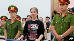 FILE - Nguyen Ngoc Nhu Quynh, center, a prominent Vietnamese blogger, stands trial in the south-central province of Khanh Hoa, Vietnam. 