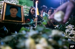 Thai anti-government protesters mourn in front of the picture of Yuthana Ong-art, who was shot and killed on Friday night, during a condolence ceremony in Bangkok, Dec. 28, 2013.