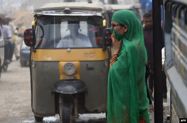 FILE - A Pakistani woman covers her face as she crosses a street in Karachi on September 27, 2016. (Photo by RIZWAN TABASSUM / AFP)