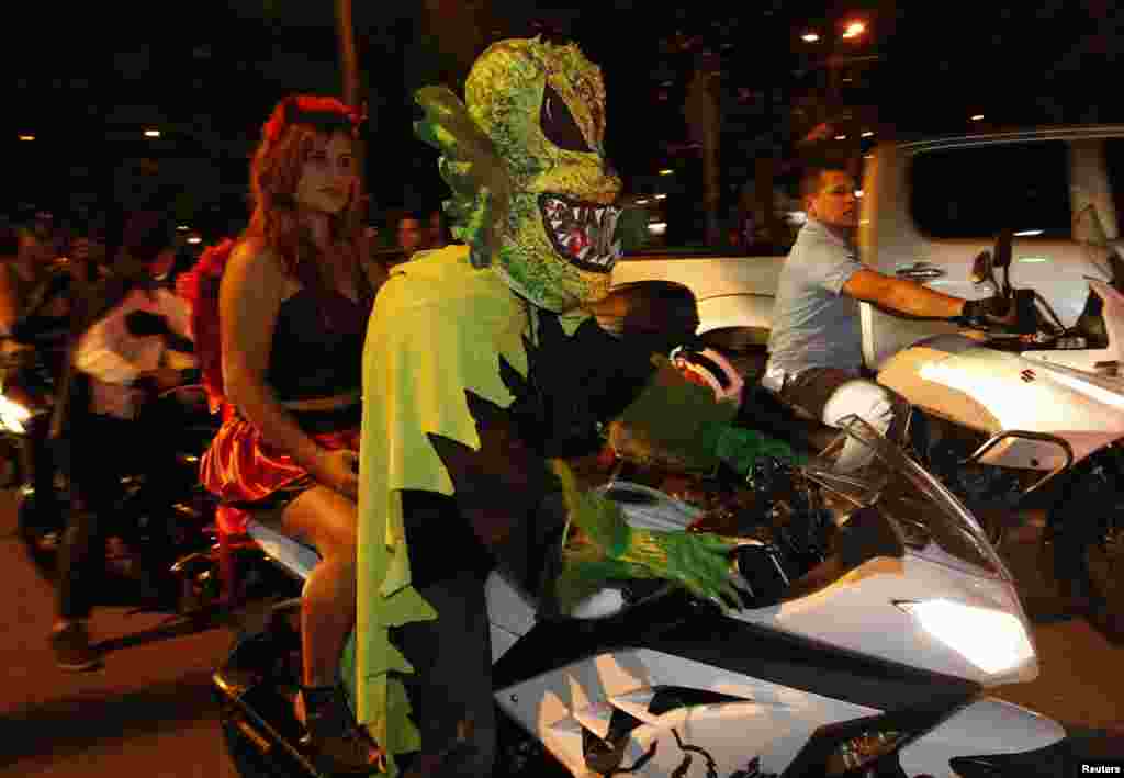 A couple dressed in costumes ride a motorbike during the "Moto Halloween Party 2013" in Cali, Colombia,  Oct. 30, 2013.
