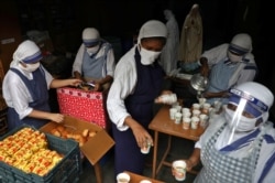 FILE - Catholic nuns from the Missionaries of Charity, the global order of nuns founded by Saint Mother Teresa, prepare to distribute free snacks and tea among the poor, in Kolkata, India, Aug. 26, 2021.