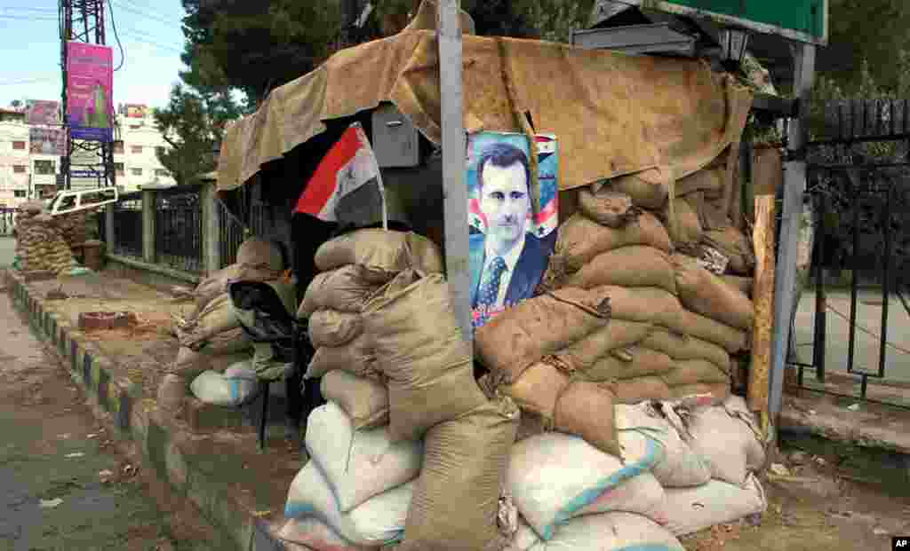 Hunkering down: a poster of Syria's president at a checkpoint on the outskirts of Damascus, Jan. 14 2012. (E. Arrott/VOA)