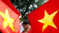 Bui Thanh Hieu, a dissident blogger, holds Vietnamese national flags while marching during an anti-China demonstration near the Chinese embassy in Hanoi July 3, 2011.