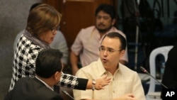 FILE - Philippine Senator Leila de Lima, center, Chairperson of the Commitee on Justice and Human Rights, tries to pacify an argument between Senator Allan Peter Cayetano, right, and Senator Antonio Trillanes IV at the Philippine Senate in Pasay, Sept. 15, 2016. 