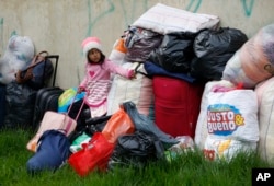 A young Venezuelan migrant waits next to her family's belongings before leaving a makeshift migrant settlement near the main bus terminal in Bogota, Colombia, Nov. 13, 2018.