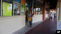 FILE - Buena Ventura Martin-Godinez, from Guatemala, holds her son, Pedro, as she walks out of a store in Homestead, Fla., on June 27, 2018. Her husband, convicted of the misdemeanor offense of illegal entry into the U.S., awaits almost certain deportation at a jail in Atlanta. 