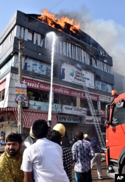 Firefighters douse a fire that broke out in a four-story commercial building in Surat, in the western state of Gujarat, India, May 24, 2019.