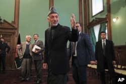 Afghan President Hamid Karzai greets journalists as he leaves a press conference in Kabul, Jan. 25, 2014.