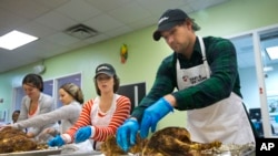 Washington Nationals baseball infielder Ryan Zimmerman, right, and his wife Heather, center, help pack turkeys for Thanksgiving meals at Food & Friends Food & Friends in Washington, Nov. 23, 2015. 