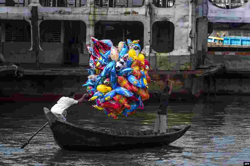 A man holds balloons as he crosses the Buriganga River on a boat in Dhaka, Bangladesh.