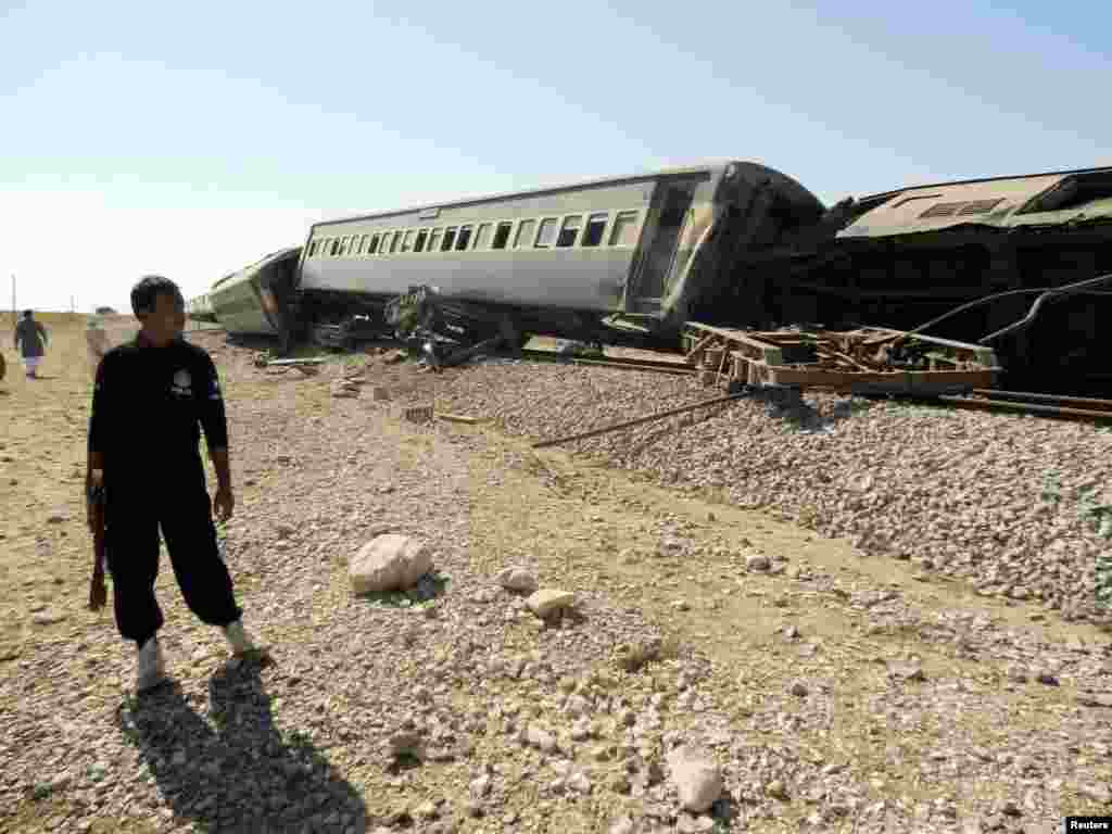 A security official stands near a passenger train that derailed after it was hit by a bomb attack in Baluchistan province, Pakistan, Oct. 21, 2013. 