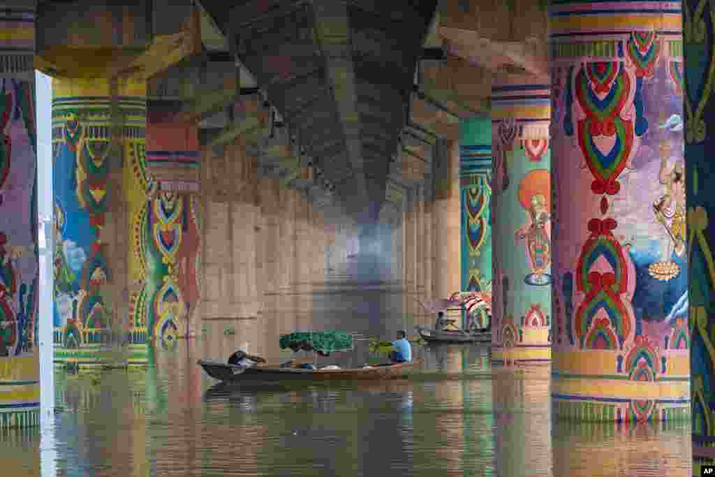 People row their boats on the swollen Ganges River in Prayagraj, India.