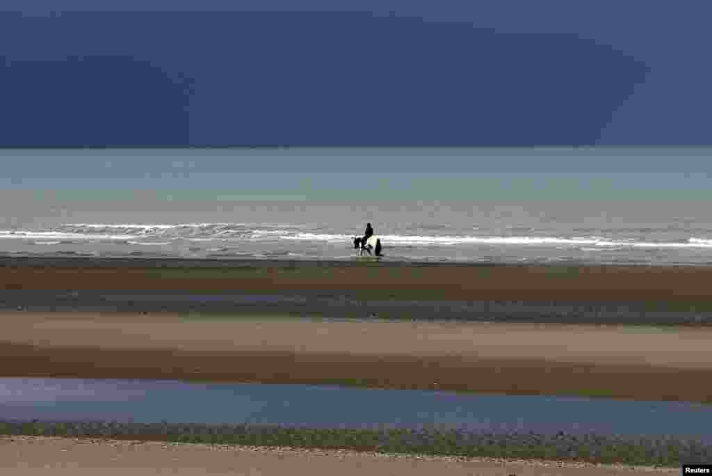 A man rides a horse along a beach in the seaside town of Zeebrugge, Belgium.