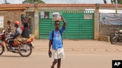 A boy selling soft drinks walk past a clinic taking care of Ebola patients in the Kenema District on the outskirts of Kenema, Sierra Leone, July 27, 2014.