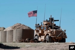 In this April 4, 2018 file photo, a U.S. soldier sits on an armored vehicle at a newly installed position, near the tense front line between the U.S-backed Syrian Manbij Military Council and the Turkish-backed fighters, in Manbij, north Syria.