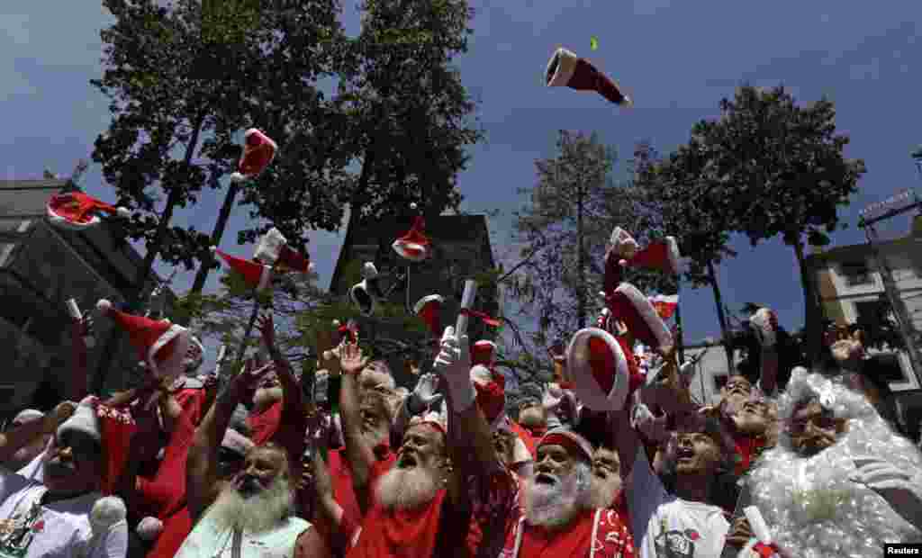 Students from the Brazilian Santa Claus school throw their hats into the air, during their graduation ceremony in Rio de Janeiro. The school holds four-day lessons in Santa-training, teaching Christmas carols, how to interact with children, and also how to wear the heavy red suit in Rio&#39;s typical 104-degree (40 degrees celsius) summer weather.