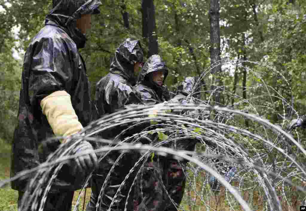 Hungarian soldiers put up spools of razor wire on Slovenian border in Zitkovci. Hungary has installed spools of razor wire near a border crossing with Slovenia, which like Hungary is part of the EU's Schengen zone of passport-free travel.
