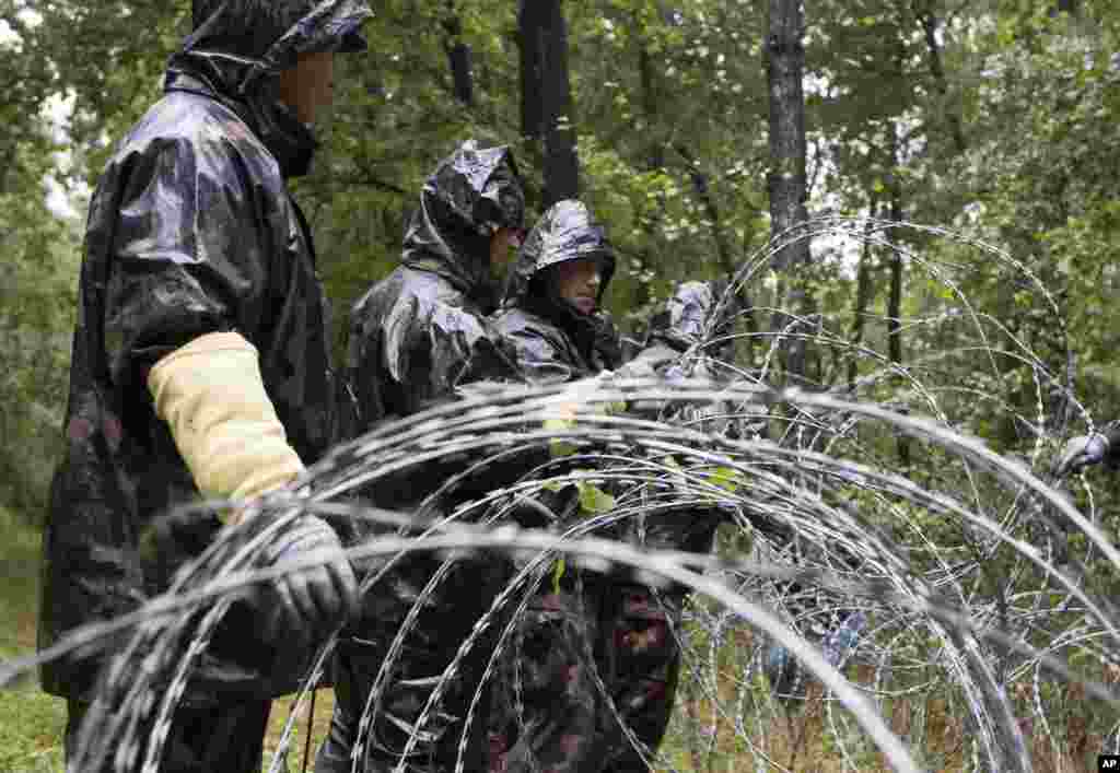 Hungarian soldiers put up spools of razor wire on Slovenian border in Zitkovci. Hungary has installed spools of razor wire near a border crossing with Slovenia, which like Hungary is part of the EU&#39;s Schengen zone of passport-free travel.