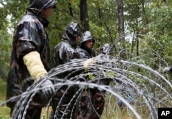 Hungarian soldiers put up spools of razor wire on Slovenian border in Zitkovci, Sept. 25, 2015. Hungary has installed spools of razor wire near a border crossing with Slovenia, which like Hungary is part of the EU's Schengen zone of passport-free travel.