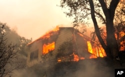 Flames from a massive wildfire consume a home on the Silverado Trail, east of Napa, Calif., Oct. 9, 2017.