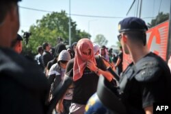 A Croatian policeman stands guard as migrants from Middle Eastern countries board a bus near the Croatia-Serbia border in Tovarnik, on Sept. 17, 2015.