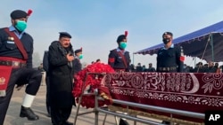 Pakistani Interior Minister Sheikh Rashid Ahmed, second left, pays tribute to a police officer, who was killed in an overnight attack, at a funeral prayer, in Islamabad, Pakistan, Jan. 18, 2022.