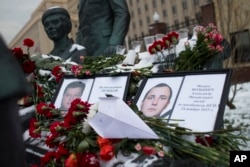 FILE - Photos of Lt.Col. Oleg Peshkov, left, and sailor Alexander Pozynich are placed at a monument to Soviet Officers with flowers and a toy jet made of paper outside Russian Army General Staff headquarters in Moscow, Nov. 26, 2015.