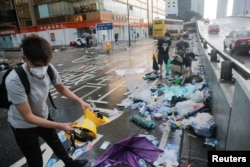 People pick out helmets, umbrellas and other items from rubbish left behind after violent clashes during a protest against a proposed extradition bill with China in Hong Kong, June 13, 2019.
