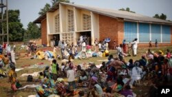 Des réfugiés musulmans assis dehors alors que des chrétiens célèbrent une messe dans une église de Boali au Nord de Bangui, République Centrafricaine, dimanche le 9 février 2014.