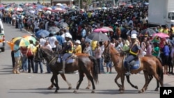 Police on horseback ride past people waiting to view the body of former South African president Nelson Mandela in Pretoria South Africa, Dec. 11, 2013. 