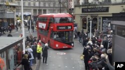 People take photos of the new routemaster double decker bus as it arrives at Victoria bus station in London on its first first day of service, Monday, Feb. 27, 2012. (AP Photo/Sang Tan)