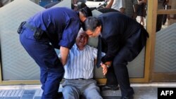 一名希臘老人在一家銀行門前向協助他的警察哭訴銀行只容許他從退休養老金戶口中提取120歐羅。