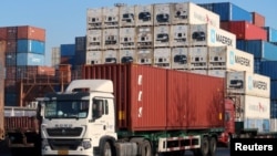 资料照片：一辆卡车运载着集装箱行驶在天津港附近一处物流中心。(2019年12月12日)