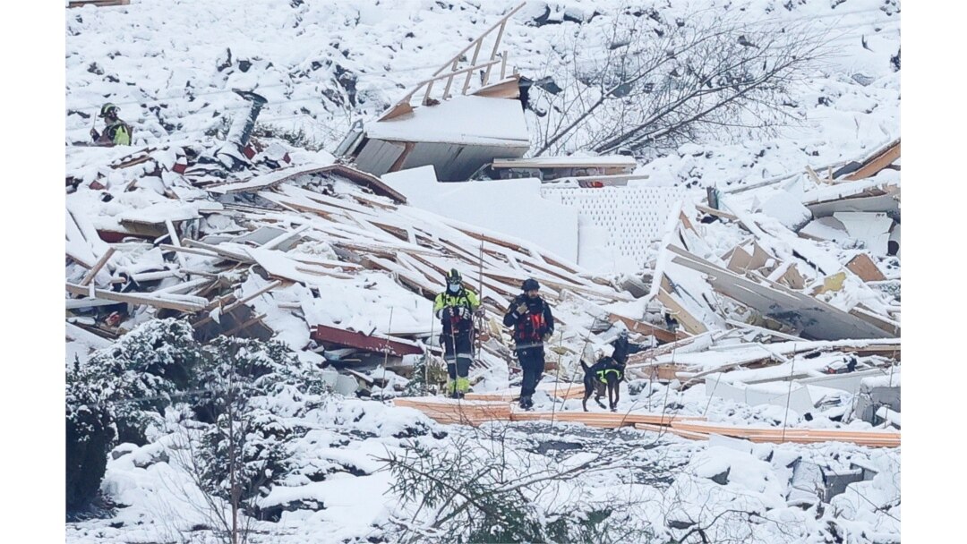 Rumah-rumah yang rata dengan tanah nampak diselimuti salju, saat Tim SAR dan seekor anjing penyelamat melakukan pencarian korban di daerah longsor di Ask, Gjerdrum, Norwegia 2 Januari 2021. (NTB / Erik Schroeder via REUTERS)