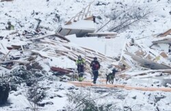 Rumah-rumah yang rata dengan tanah nampak diselimuti salju, saat Tim SAR dan seekor anjing penyelamat melakukan pencarian korban di daerah longsor di Ask, Gjerdrum, Norwegia 2 Januari 2021. (NTB / Erik Schroeder via REUTERS)