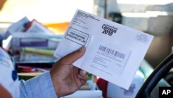 US Postal Service mail carrier Thomas Russell holds a census form while working his route in 2010.The U.S. Commerce Department has announced that the 2020 U.S. Census will include a question about citizenship status. (AP Photo/Jason E. Miczek)