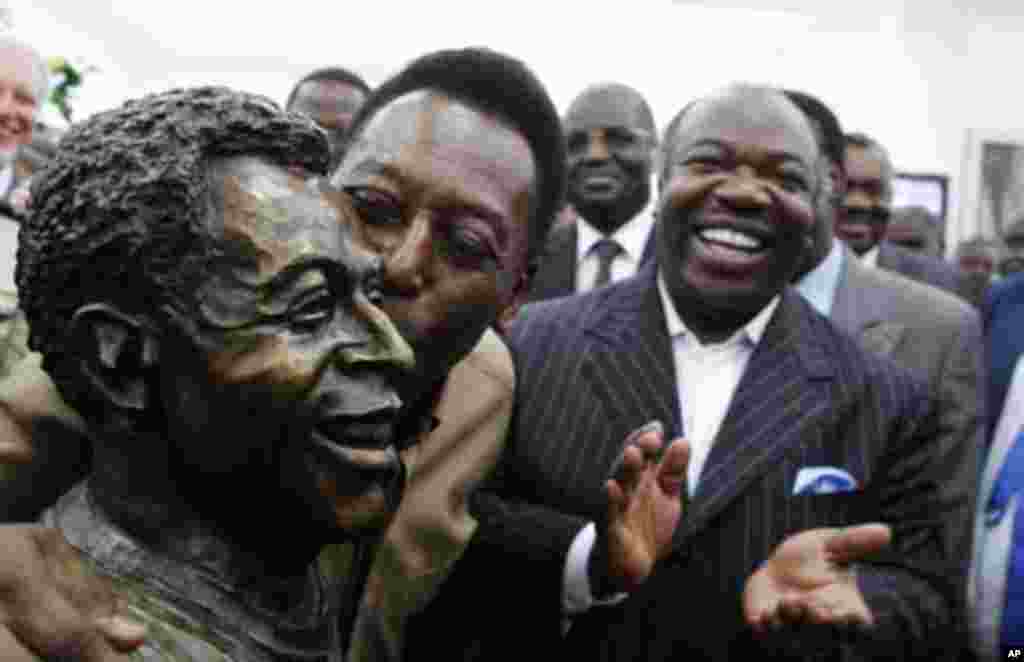 Gabon's President Ali Bongo Ondimba (R) watches as Brazil's soccer legend Pele kisses his statue during its inauguration inside the Stade De L'Amitie Stadium in Gabon's capital Libreville, February 9, 2012.