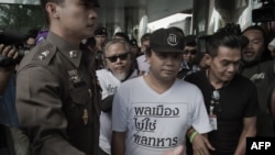 Two demonstrators (in white t-shirts) are arrested by police officers during a rally in Bangkok on May 22, 2015. 