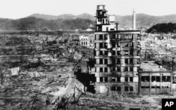 FILE - In this Aug. 8, 1945, photo, survivors walk past one of the few buildings still standing two days after the United States dropped an atomic bomb on Hiroshima, Japan.