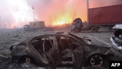 This photo taken on August 13, 2015 shows a destroyed car as a fire continues to burn after a series of explosions at a chemical warehouse hit the city of Tianjin, in northern China. 