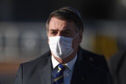 Presiden Jair Bolsonaro, mengenakan masker setibanya di Istana Alvorada, Brasilia, untuk mengikuti upacara pengibaran bendera sebelum pertemuan menteri, 12 Mei 2020. (Foto: dok).