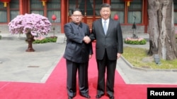 North Korean leader Kim Jong Un shakes hands with Chinese President Xi Jinping in Beijing, as he paid an unofficial visit to China, in this undated photo released by North Korea's Korean Central News Agency in Pyongyang, March 28,2018.