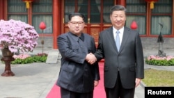 North Korean leader Kim Jong Un shakes hands with Chinese President Xi Jinping in Beijing, as he paid an unofficial visit to China, in this undated photo released by North Korea's Korean Central News Agency in Pyongyang, March 28, 2018. 