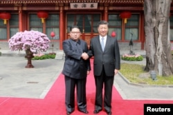 North Korean leader Kim Jong Un shakes hands with Chinese President Xi Jinping in Beijing, as he paid an unofficial visit to China, in this undated photo released by North Korea's Korean Central News Agency in Pyongyang, March 28, 2018.
