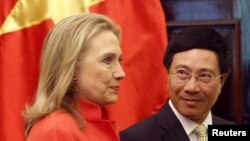 Vietnam's Foreign Minister Pham Binh Minh (R) looks at U.S. Secretary of State Hillary Clinton as they walk to the meeting room at the Government Guest House in Hanoi, July 10, 2012. 