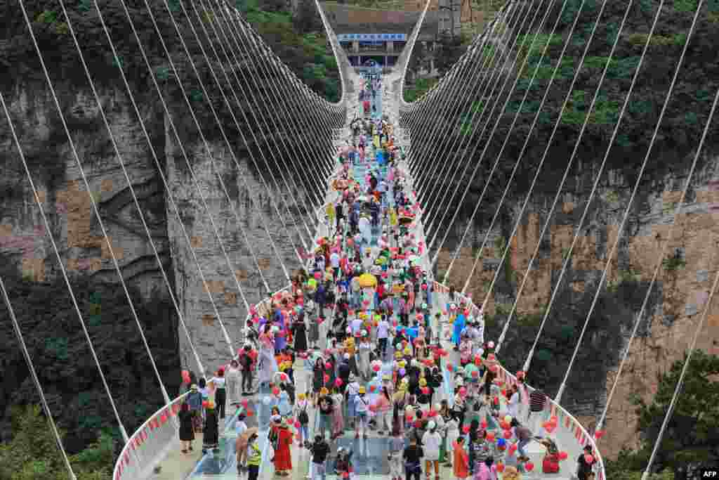 People walk on a glass-bottomed skywalk in Zhangjiajie, in China&#39;s central Hunan province, June 20, 2021.
