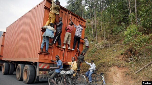 Young people, some on bicycles, hang to the back of a truck outside the capital Bujumbura, Burundi, July 19, 2015.