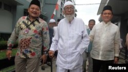 Abu Bakar Bashir, center, the alleged mastermind of the 2002 Bali bombings, walks as he is visited by Yusril Ihza Mahendra, right, who is the lawyer of Indonesia's presidential candidate Joko Widodo, at Gunung Sindur prison in Bogor, Indonesia, Jan. 18, 2019. 